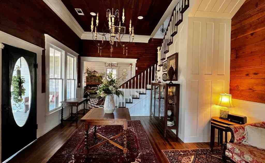 Entry hall of the Dover House in Florien with wood-paneled walls, staircase, chandelier, and original front door